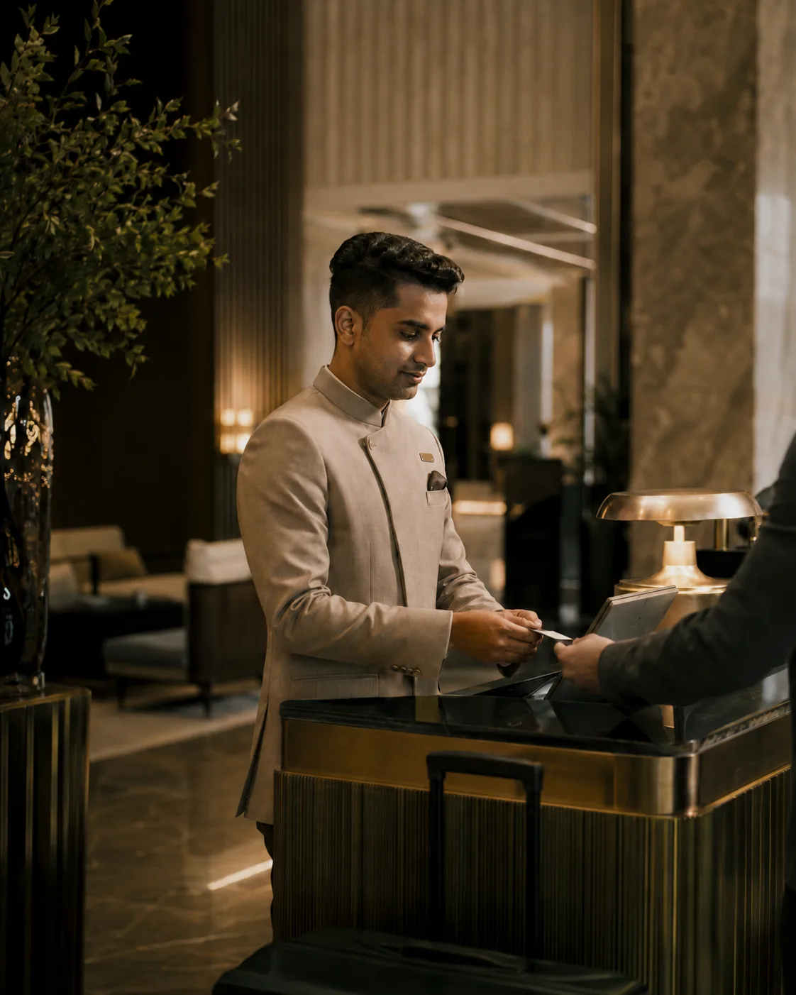 South Asian front office professional assisting a guest in a premium hotel